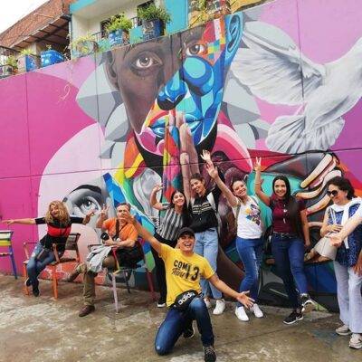 Grupo diverso de turistas interactuando con arte urbano durante un recorrido guiado por la Comuna 13